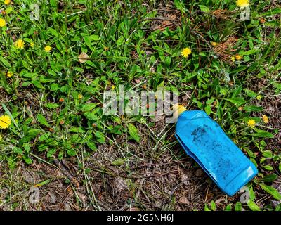 Un bidon en plastique bleu dans un jardin de junkyard dans l'herbe verte. Récipient pour produits chimiques. Couvercle jaune. Produits chimiques automobiles. Pollution de l'environnement. PLASTI Banque D'Images