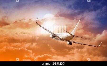 Passagers avion commercial survolant les nuages dans la lumière du coucher du soleil. Banque D'Images