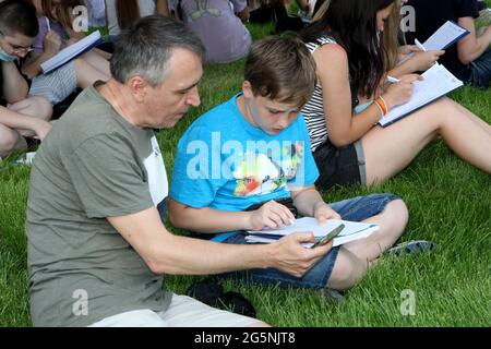 DNIPRO, UKRAINE - 28 JUIN 2021 - UN homme aide un garçon à prendre une dictée en ukrainien près de la place Tarasa Shevchenko pour célébrer le 25 Banque D'Images
