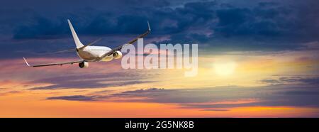 Passagers avion commercial survolant les nuages dans la lumière du coucher du soleil. Banque D'Images