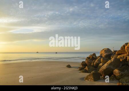 Couleur pastel cirrostratus nuageux plage tropicale lever de soleil paysage marin. Front de mer à l'aube avec un affleurement rocheux. Huay Yang, Thaïlande. Banque D'Images