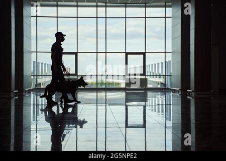 Un agent de sécurité et un chien de police se prometant dans le terminal de l'aéroport Banque D'Images