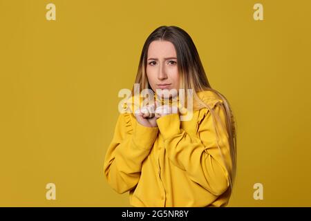 femme blonde effrayée sur fond jaune. Émotions humaines Banque D'Images