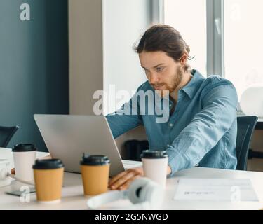Un jeune travailleur de bureau a été stressé et a essayé de se concentrer tout en travaillant sur un ordinateur portable Banque D'Images
