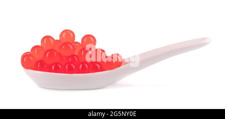 Perles de tapioca rouges pour le thé à bulles isolées sur fond blanc. Perles de tapioca dans une cuillère en céramique. Banque D'Images
