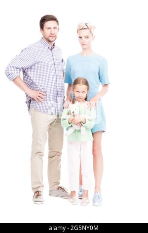 Prise de vue verticale isolée sur toute la longueur de la famille avec un enfant debout ensemble regardant la caméra avec des expressions faciales sérieuses, fond blanc Banque D'Images