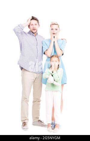 Prise de vue verticale en longueur d'un homme et d'une femme modernes debout avec leur petite fille s'étonnait de quelque chose, sur fond blanc Banque D'Images