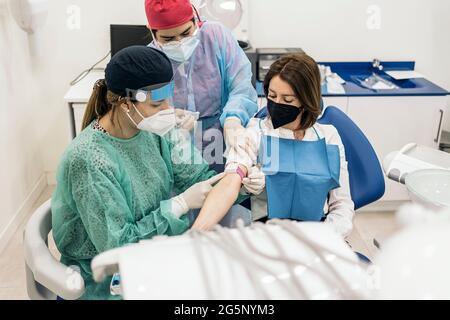 Professionnels travailleurs de la méditation portant des gants en latex tirant du sang à la patiente. Banque D'Images