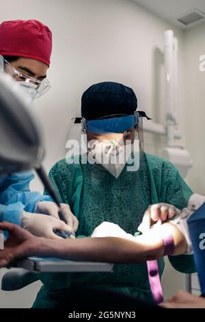 Professionnels les travailleurs de la méditation portant des gants en latex tirant du sang à un patient non reconnu. Banque D'Images