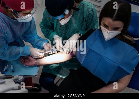 Professionnels travailleurs de la méditation portant des gants en latex tirant du sang à la patiente. Banque D'Images