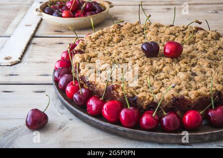 Tarte aux cerises aux saupoudrées, crumble aux cerises et cerises fraîches sur fond de bois rustique Banque D'Images