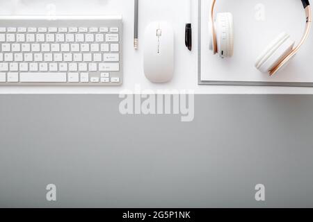 Vue de dessus de l'espace de travail. Bureau table bureau avec clavier, casque souris fournitures de bureau sur table blanche tapis gris. Espace de travail moderne à plat avec copie Banque D'Images