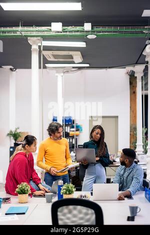 Travail d'équipe diversifié en parlant et en utilisant des ordinateurs portables dans un bureau moderne et lumineux. Concept de collaboration Banque D'Images
