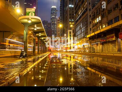 Belles couleurs et réflexions à un arrêt de tramway à Hong Kong après une tempête. Une exposition prolongée la nuit a donné des traînées de lumière des bus et des tramways. Banque D'Images