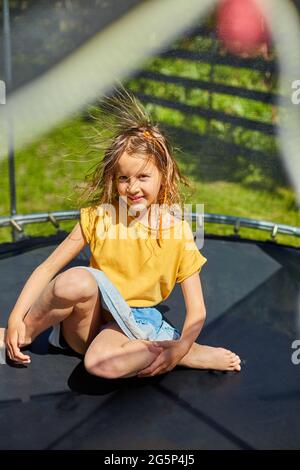 Portrait de jeune fille avec des cheveux électrifiés sur trampoline en plein air, dans l'arrière-cour de la maison sur un jour ensoleillé d'été, vacances d'été, heureux li Banque D'Images