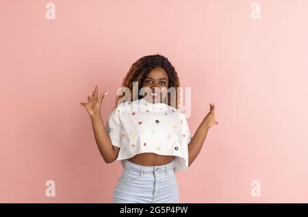 Jolie jeune femme afro-américaine en vêtements décontractés posant sur le backgroung de pêche démontrant diverses émotions. Banque D'Images