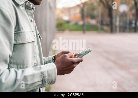 Un jeune africain non reconnu se tenant dans la rue et utilisant son téléphone portable. Banque D'Images