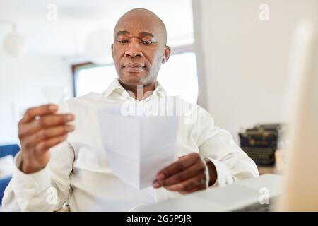 L'homme afro-américain travaillant à domicile lit les instructions pour l'auto-test du coronavirus à la maison Banque D'Images