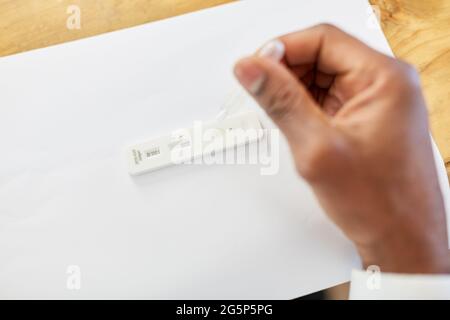 La main avec la pipette et l'échantillon de salive fait le diagnostic avec un test rapide Covid-19 à la maison Banque D'Images