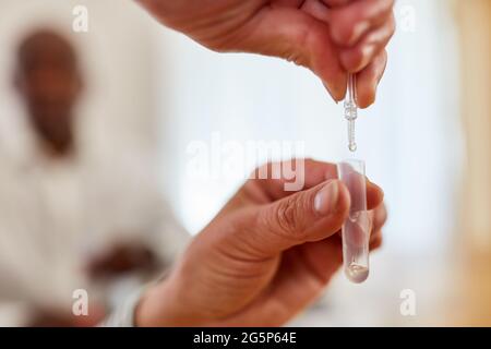 Pipette et tube à main avec échantillon de salive pour test rapide Covid-19 à domicile Banque D'Images