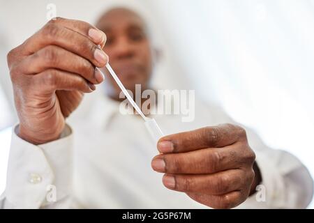 Man effectue un test de diagnostic rapide Covid-19 comme test d'antigène à la maison avec un échantillon de salive Banque D'Images