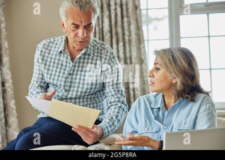 Un couple mature chez lui ayant des arguments sur les finances intérieures Banque D'Images