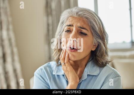 Femme mature à la maison souffrant de douleur avec mal de dents Banque D'Images