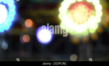 Lumières de bokeh démoussantes faites d'attractions effrayantes tournant dans Luna Park Banque D'Images