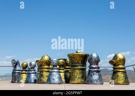 Jeu d'échecs géant avec des pièces d'or et d'argent dehors sur le fond du ciel clair. Banque D'Images