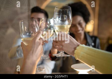 Groupe de jeunes heureux qui se trinquent des verres à vin assis à la table du restaurant. Concept de mode de vie pour les jeunes avec des amis qui s'amusent à boire du vin blanc Banque D'Images