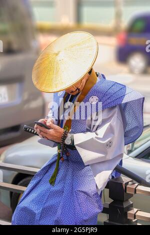 tokyo, japon - avril 06 2019 : homme âgé japonais avec un smartphone à la main portant pendant la procession nerigyoretsu du temple zojoji un traditionnel Banque D'Images