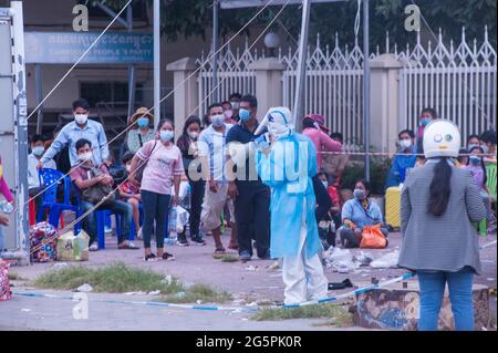 Phnom Penh, Cambodge. Le 29 juin 2021. Pendant 4 mois, Phnom Penh affronte une vague de COVID - 19. Un EMT dans l'EPI complet dirige un site de tests de masse. Un groupe de Cambodgiens qui ont tous été testés positifs pour le virus attendent d'être pris en charge par les ambulances. Credit: Kraig Lieb / Alamy Live News Banque D'Images