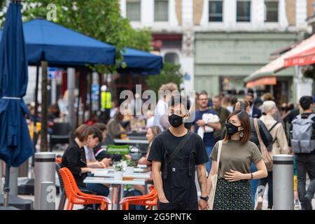 Les gens portent des couvre-visage à Kensington, Londres, alors que le gouvernement continue de surveiller les niveaux d'infection par le coronavirus avant la fin potentielle des restrictions sur les coviles le 19 juillet. Date de la photo: Mardi 29 juin 2021. Banque D'Images