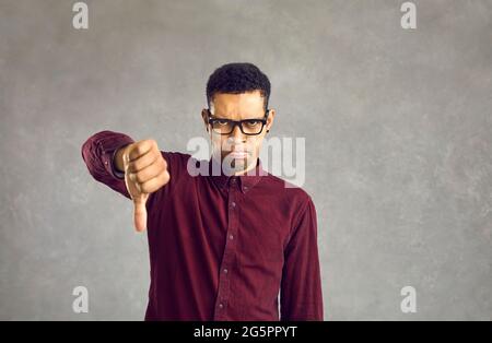 Frognant homme afro-américain montrant des commentaires négatifs et n'aime pas le studio tourné Banque D'Images