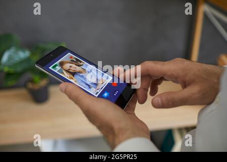 L'homme regarde à travers une photo d'une jeune femme européenne sur son smartphone, clique je l'aime Banque D'Images