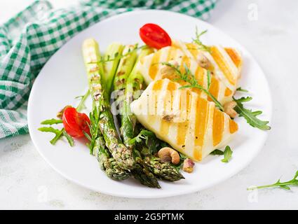 Salade de fromage halloumi grillé avec tomates et asperges sur plaque sur fond clair. Nourriture végétarienne saine. Banque D'Images