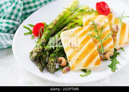 Salade de fromage halloumi grillé avec tomates et asperges sur plaque sur fond clair. Nourriture végétarienne saine. Banque D'Images