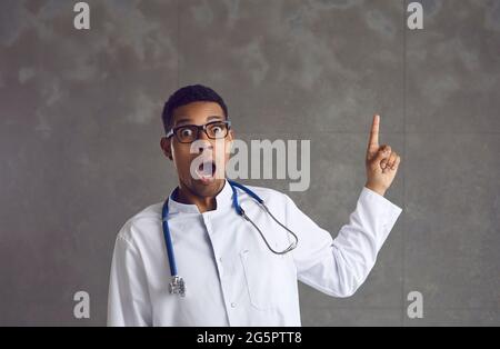Un médecin américain afro-américain choqué pointe vers le haut le portrait du studio Banque D'Images