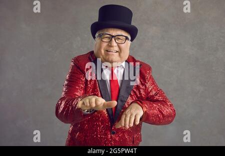 Drôle de gros homme senior dans une veste rouge à paillettes ayant le plaisir à une soirée disco rétro fou Banque D'Images