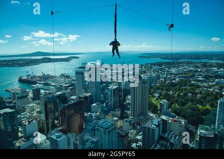 Une personne est suspendue en plein air juste avant de faire une chute de ciel captive de la Tour du ciel à Auckland, Île du Nord, Nouvelle-Zélande, avec des bâtiments de la ville au-delà Banque D'Images