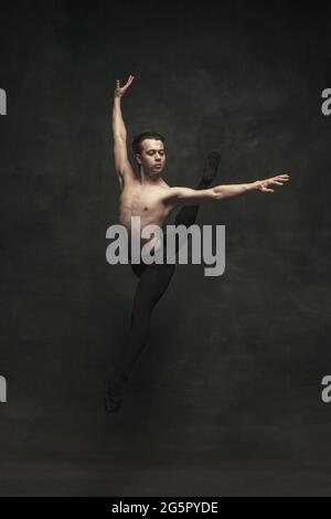 Jeune danseur de ballet masculin élégant isolé sur fond sombre. Art, action, inspiration. Banque D'Images