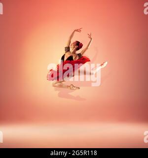 Jeune et incroyablement belle ballerine pose et danse dans un studio rouge plein de lumière. Banque D'Images