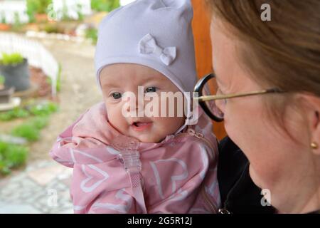 La petite fillette dans un chapeau blanc et des vêtements roses est souriante et est heureuse Banque D'Images