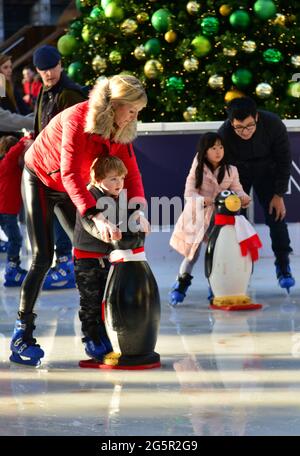 ROYAUME-UNI. ANGLETERRE. LONDRES. LES PARENTS APPRENANT LE PATINAGE SUR GLACE À LEURS ENFANTS SUR LA PATINOIRE MIS POUR NOËL DANS LES JARDINS DE L'HISTOIRE NATURELLE MU Banque D'Images