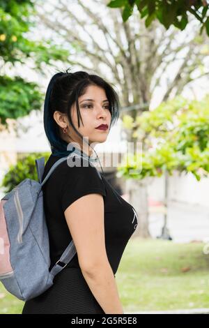 Fille à poil bleu de l'université latine marchant dans le parc vêtue de noir Banque D'Images