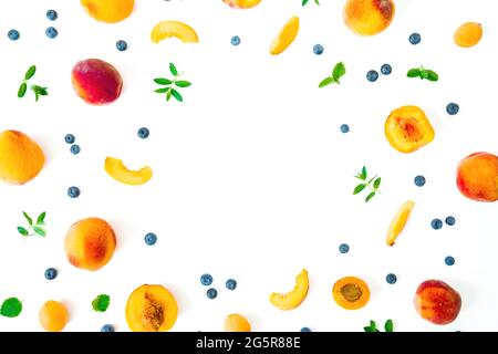 Pêche savoureuse avec baies bleues et feuilles de menthe isolées sur blanc. Fruits d'été. Vue de dessus. Pose à plat Banque D'Images
