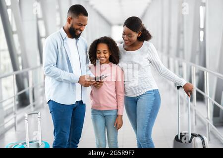 Bonne famille noire voyageant, en tenant des documents à l'aéroport Banque D'Images