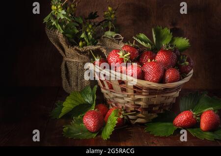 baies de fraises mûres sur fond de bois sombre dans un style rustique Banque D'Images