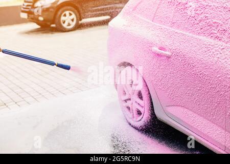 Lavage manuel de voiture avec de l'eau sous pression dans les lavages de voiture, une personne lave la mousse de la voiture avec de l'eau haute pression Banque D'Images