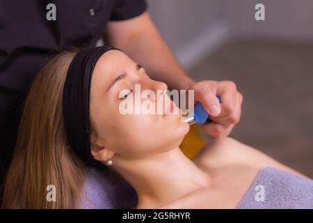 Femme reçoit de rajeunissement du visage massage du visage saigner à l'acupuncture wellness spa Banque D'Images